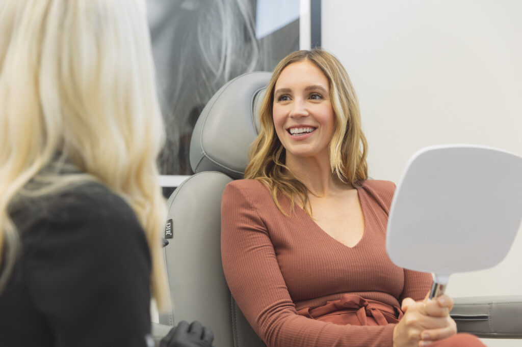 woman smiles in mirror after sculptra in OKC