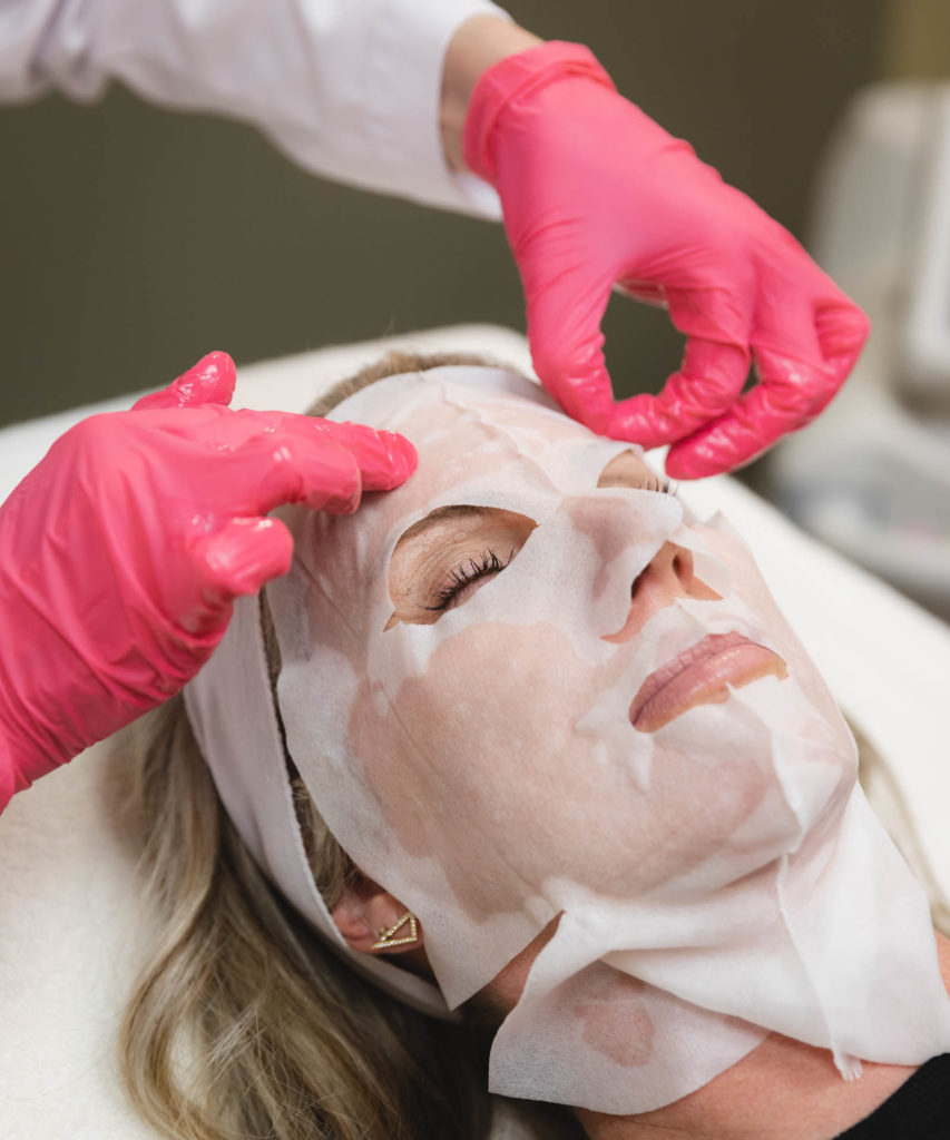 close up of gloved hands applying a dry skin treatments in Oklahoma City on a woman