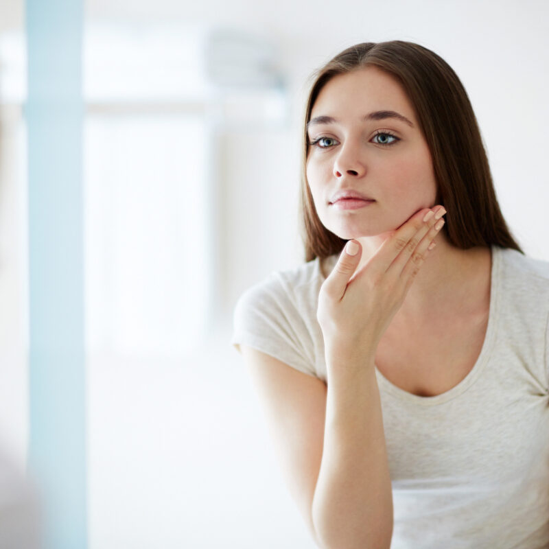woman looking in mirror considering skincare steps