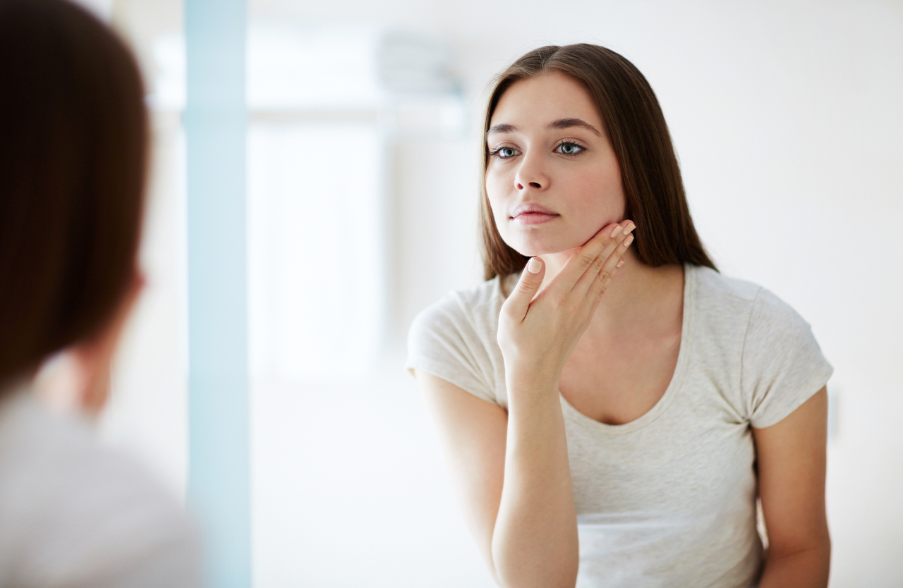 woman looking in mirror considering skincare steps