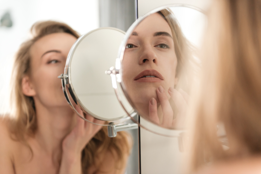 young blonde woman looking at reflections after sculptra in Oklahoma City