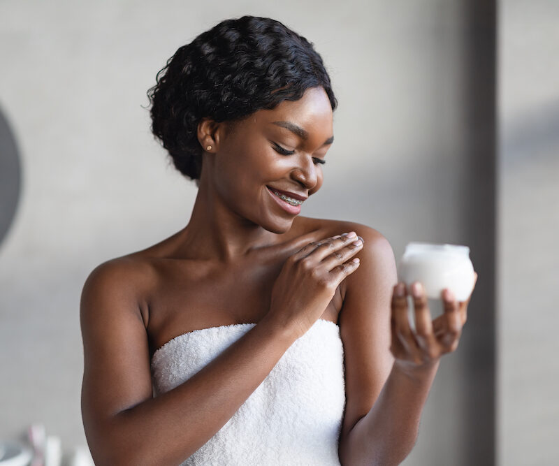 A smiling young woman applies lotion after a shower before a dry skin treatments in Oklahoma City