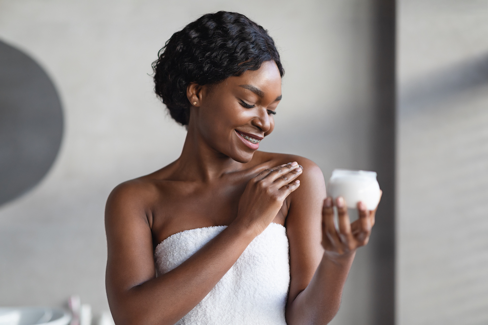 A smiling young woman applies lotion after a shower before a dry skin treatments in Oklahoma City